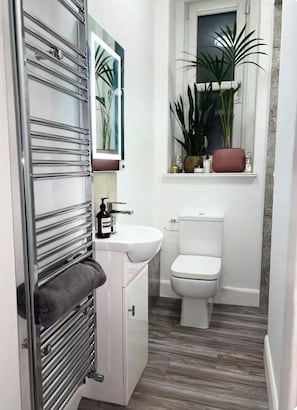 A bathroom with a white sink, a toilet, a towel rack, and a mirror. - Luxury Leith Apartment | Stylish Edinburgh Stay (Edinburgh)