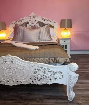 Ein Bett mit einem verzierten Kopfteil, einer Nachttischlampe und einem Nachttisch.