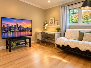 A modern living room with a flat-screen TV, a desk, a chair, a sofa, and a window with curtains. - White Rock Suite + 3-min drive to the Beach (White Rock)