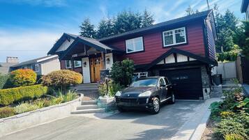A two-story house with a black car parked in the driveway.