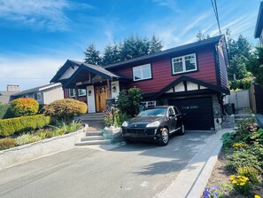 A two-story house with a black car parked in the driveway.