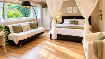 A bedroom with a bed, a sofa, a bedside table, a lamp, and a window with curtains.