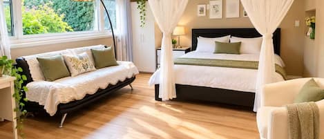 A bedroom with a bed, a sofa, a bedside table, a lamp, and a window with curtains.