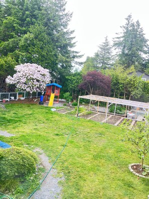 A garden with a playhouse, a pergola, and a variety of plants.