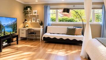 A bedroom with a bed, a desk, a chair, a television, and a window with curtains.