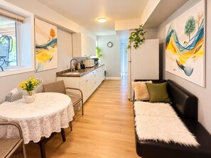 A compact living space with a dining area, a sofa, and a kitchenette.