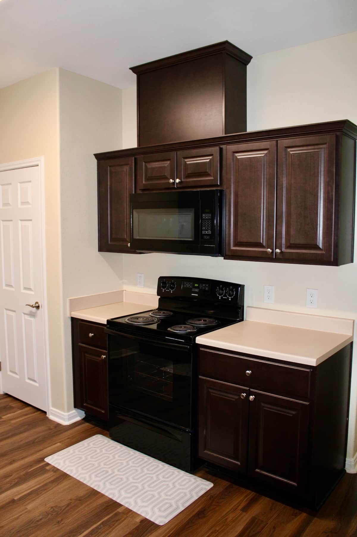 A kitchen with dark wooden cabinets, a black stove, and a microwave.