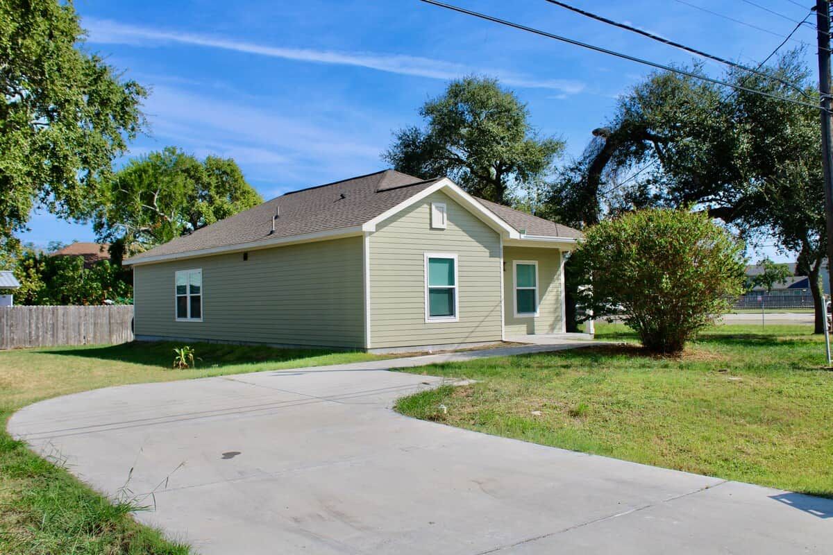 A single-story house with a front yard, a driveway, and a small tree.