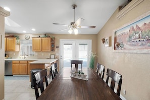 A kitchen with wooden cabinets, a dining table with chairs, a ceiling fan, and a painting on the wall. - Lake Havasu Getaway w/ Boat Parking & Pool - Sleeps 10! (Lake Havasu City)