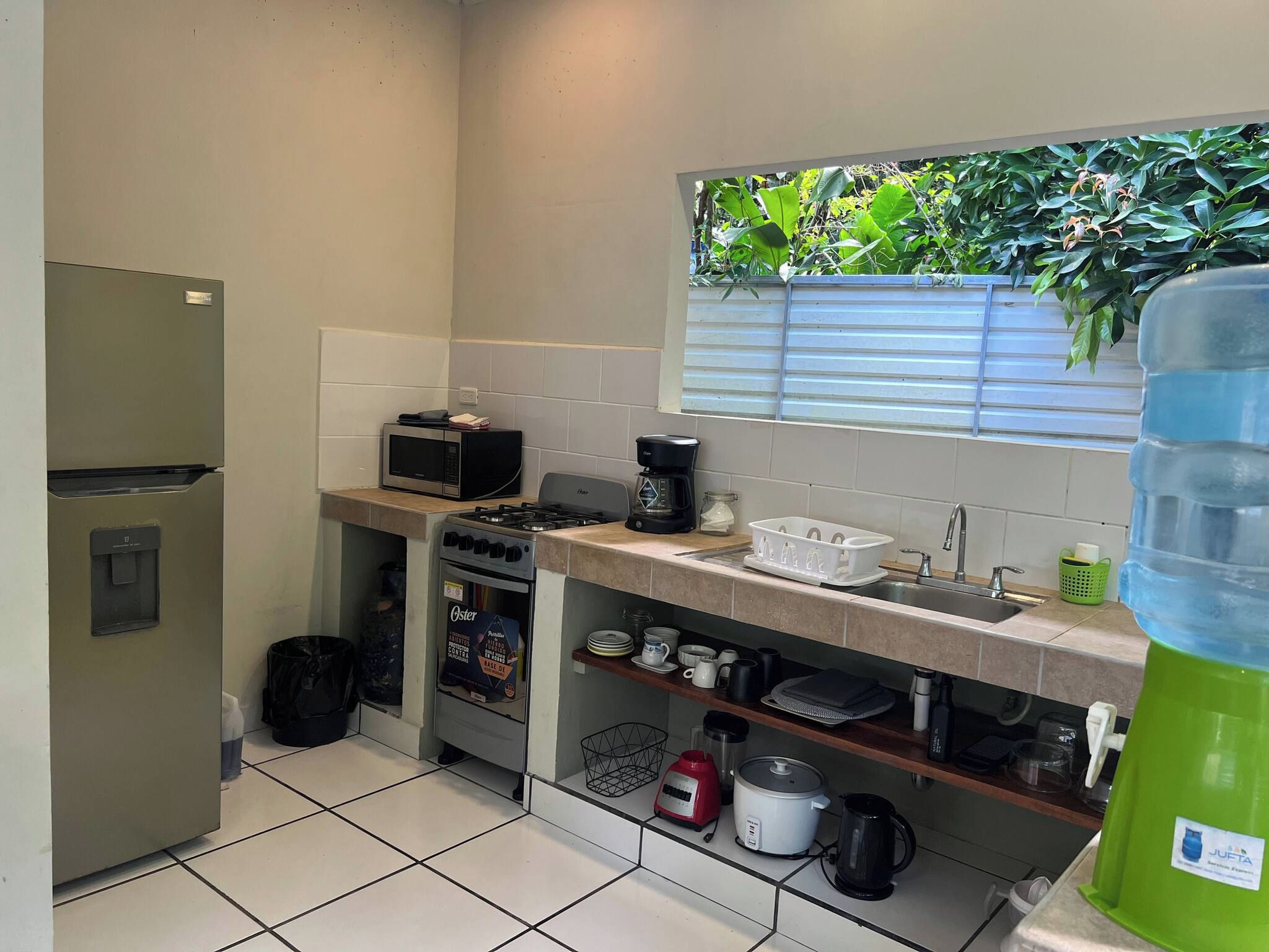 A compact kitchen with a refrigerator, microwave, stove, and sink.