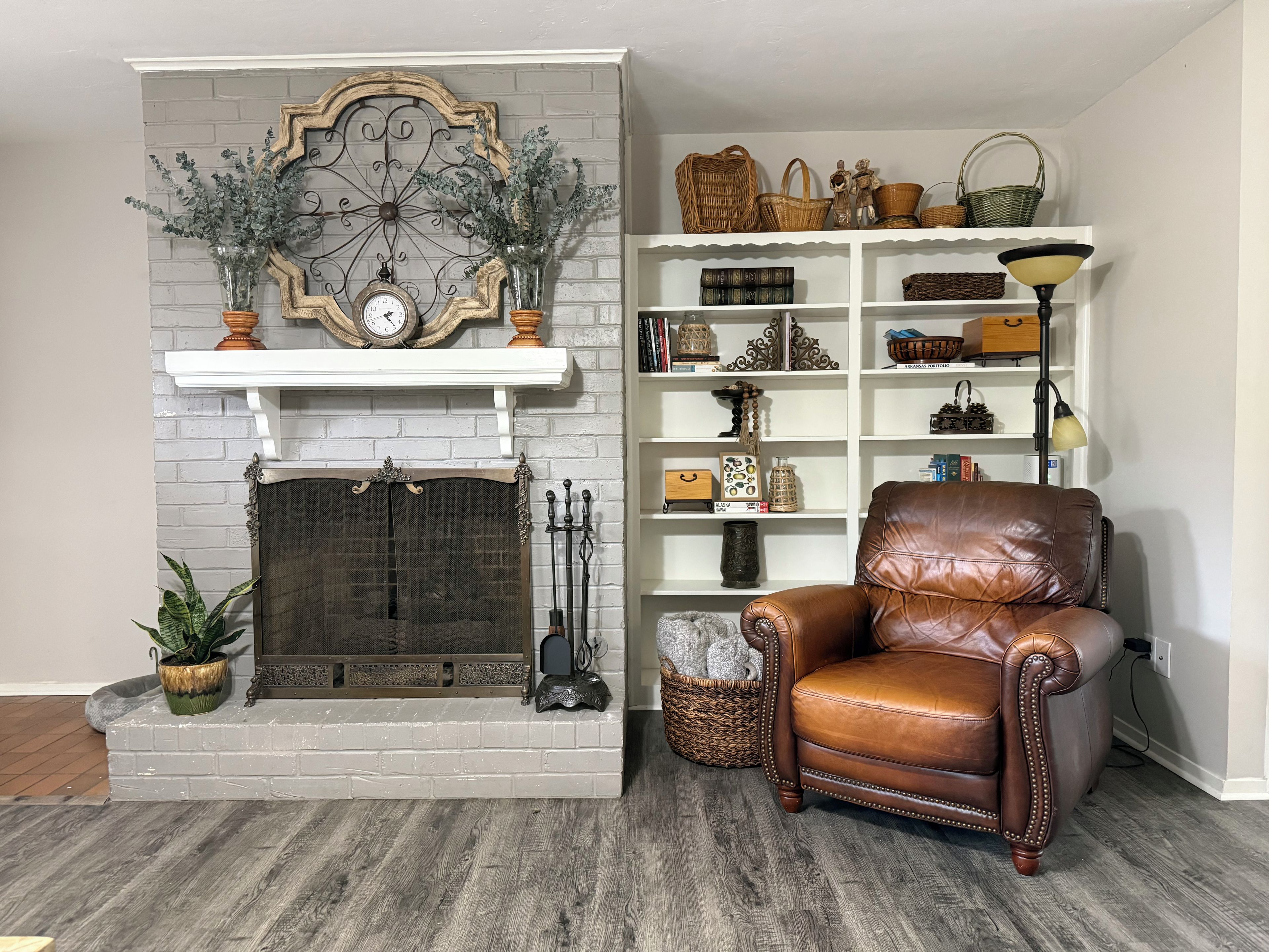 A room with a fireplace, a leather armchair, and a bookshelf with various decorative items.