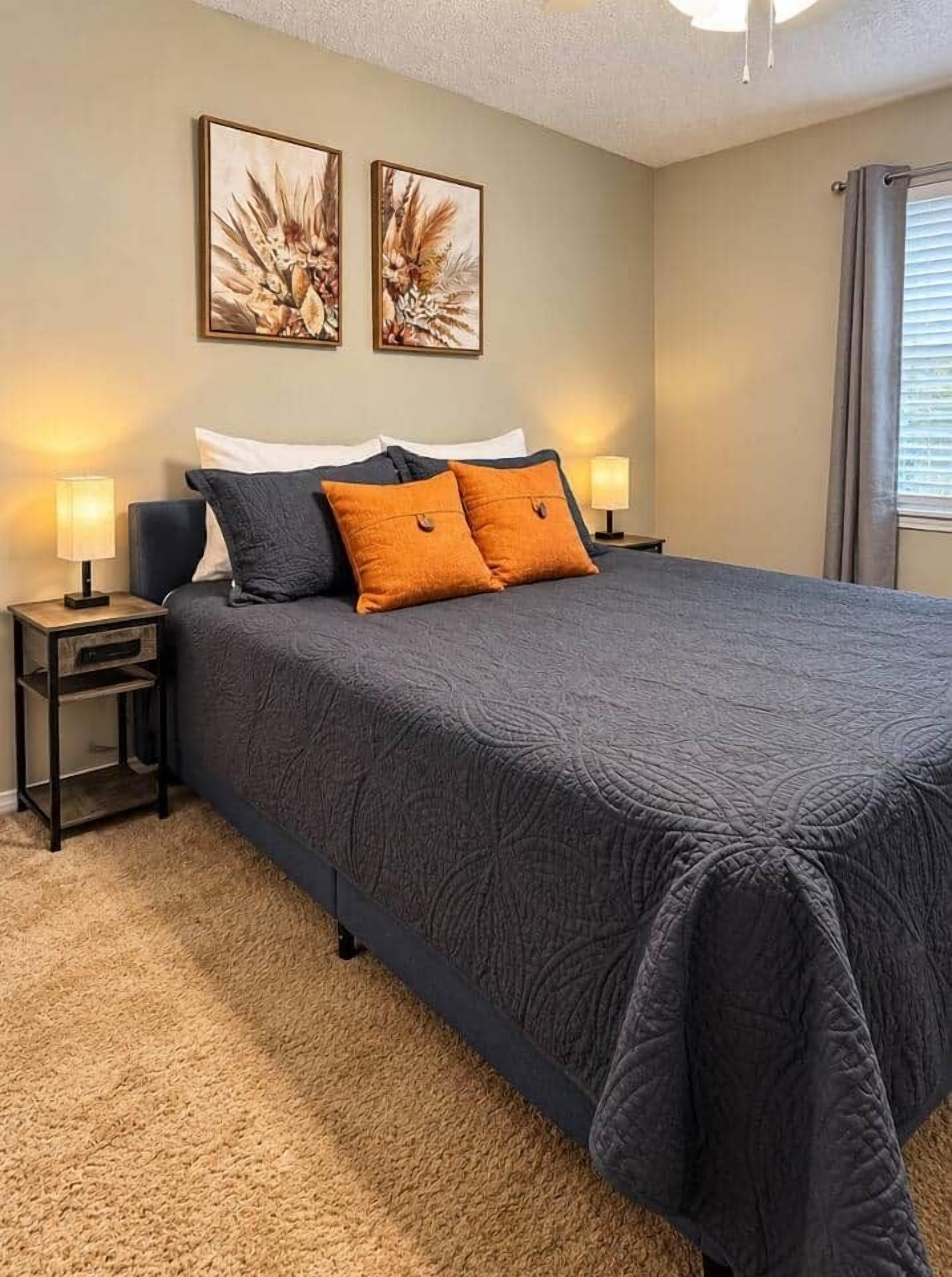 A bedroom with a large bed, two bedside tables, and wall art.