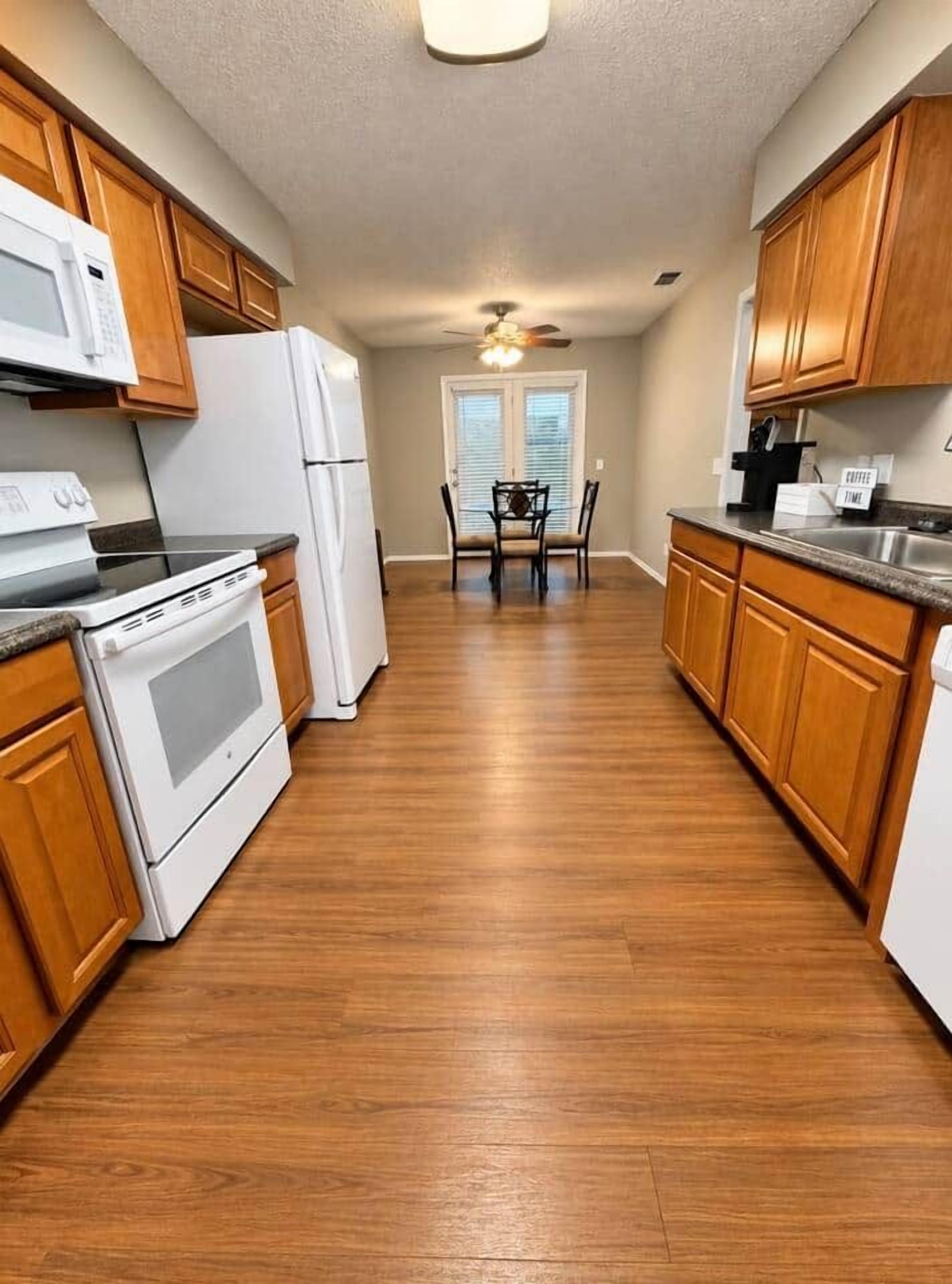 Una cocina con armarios de madera, un refrigerador blanco, un microondas y una estufa.