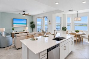 A modern kitchen with a large island, dining area, and a view of the water. - Stunning Lakefront Calusa Country Club Condo - A Slice Of Paradise (Bradenton)