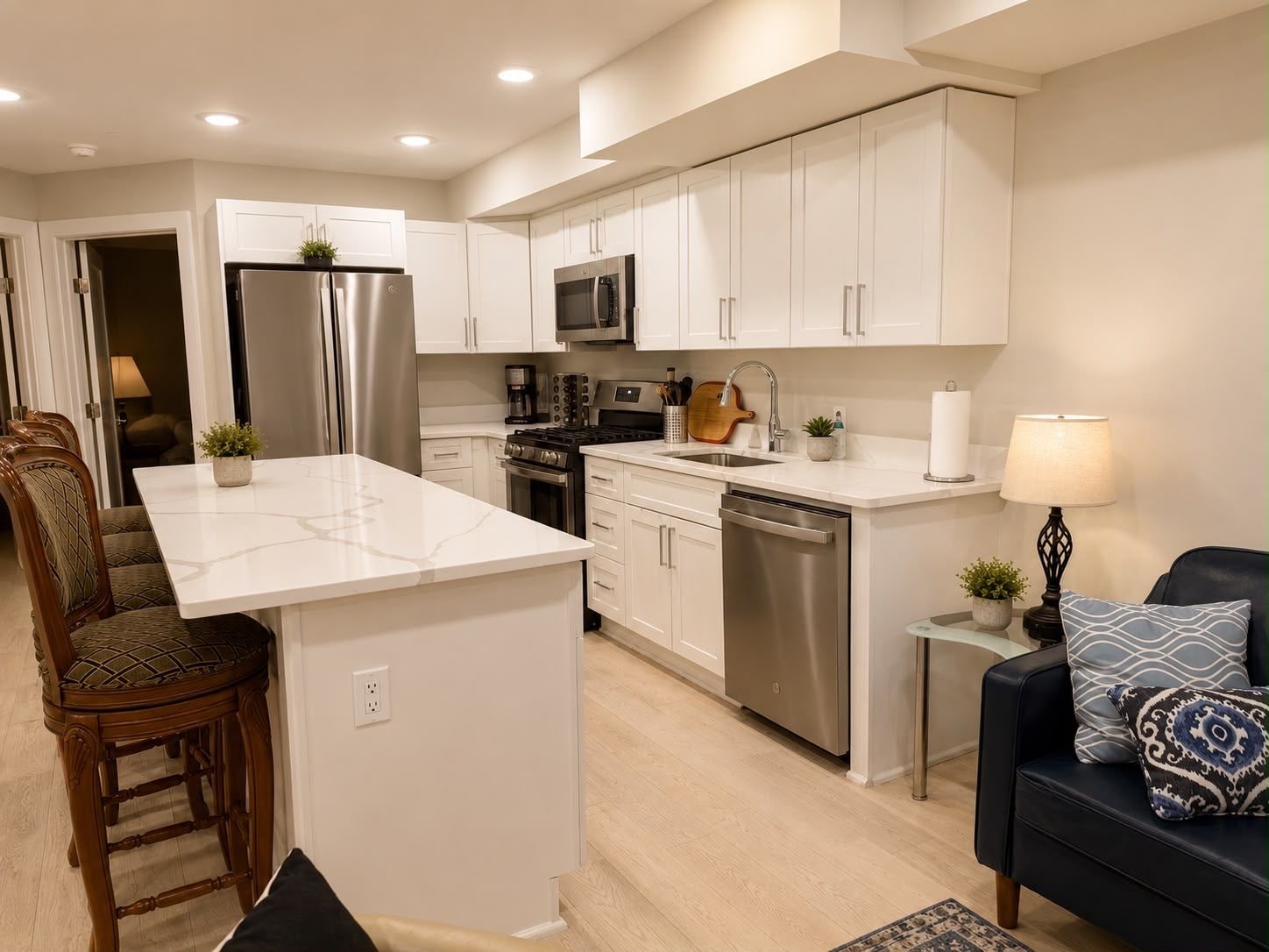 A modern kitchen with white cabinetry, stainless steel appliances, and a central island.