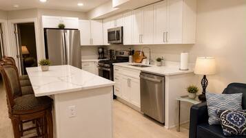 A modern kitchen with white cabinetry, stainless steel appliances, and a central island.