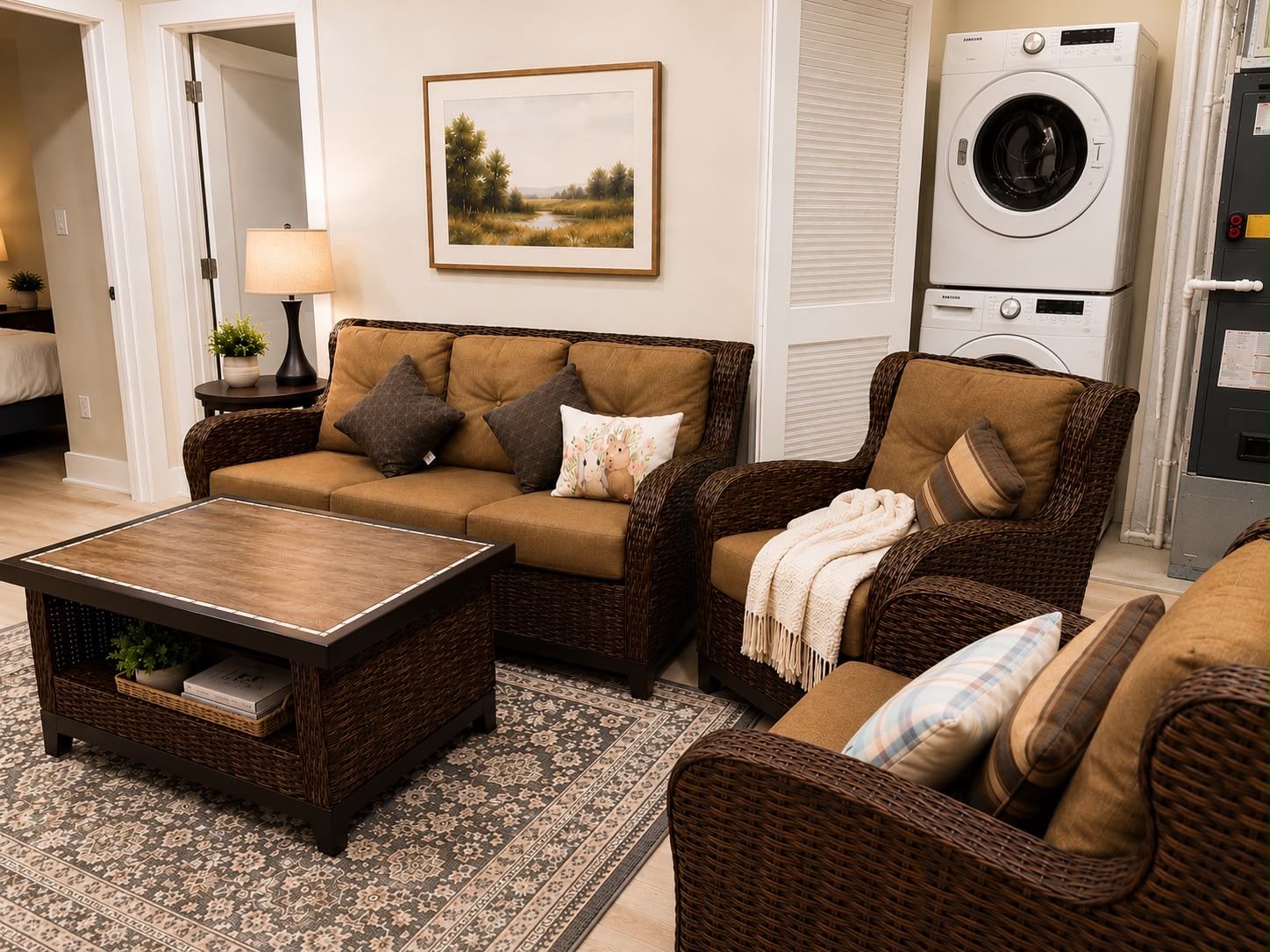 A living room with a sofa, armchair, coffee table, and a washing machine in the background.