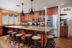 A kitchen with a central island, bar stools, stainless steel appliances, and wooden cabinetry. - The Cabin on Pine Creek (Cammal)