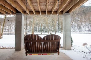 A wooden swing set under a covered area with a view of a snowy landscape. - The Cabin on Pine Creek (Cammal)