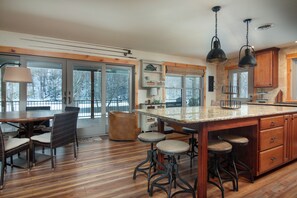 A spacious kitchen with a large island, bar stools, and a dining area with chairs. - The Cabin on Pine Creek (Cammal)