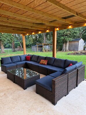 An outdoor patio with a sectional sofa and a glass-top coffee table. - Southern Comfort Retreat (Theodore)