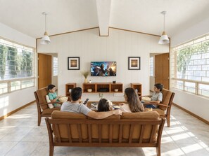 A living room with a sofa set, a television, and a window with a view. - Quinta San Gabriel | Cabin with Jacuzzi, Garden, Fire Pit, and Peace (Atlixco)