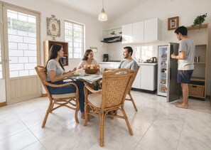A modern kitchen with a dining table, wicker chairs, and a person standing by the refrigerator. - Quinta San Gabriel | Cabin with Jacuzzi, Garden, Fire Pit, and Peace (Atlixco)