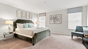 A bedroom with a bed, bedside tables, a chair, and artwork on the walls. - 6BR Champions Gate Pool, Hot Tub & Near Disney (Four Corners)
