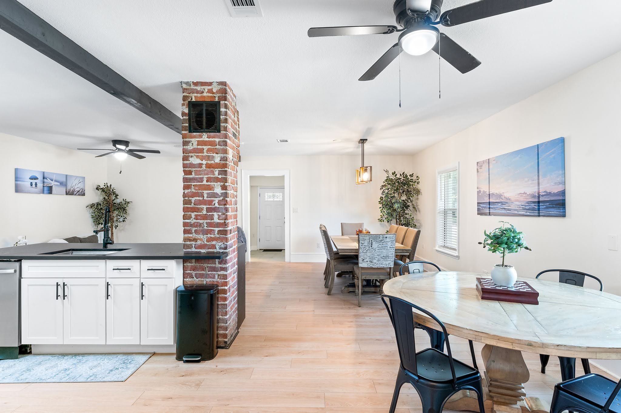 A modern kitchen with a brick chimney, wooden flooring, and a dining area with a round table and chairs.