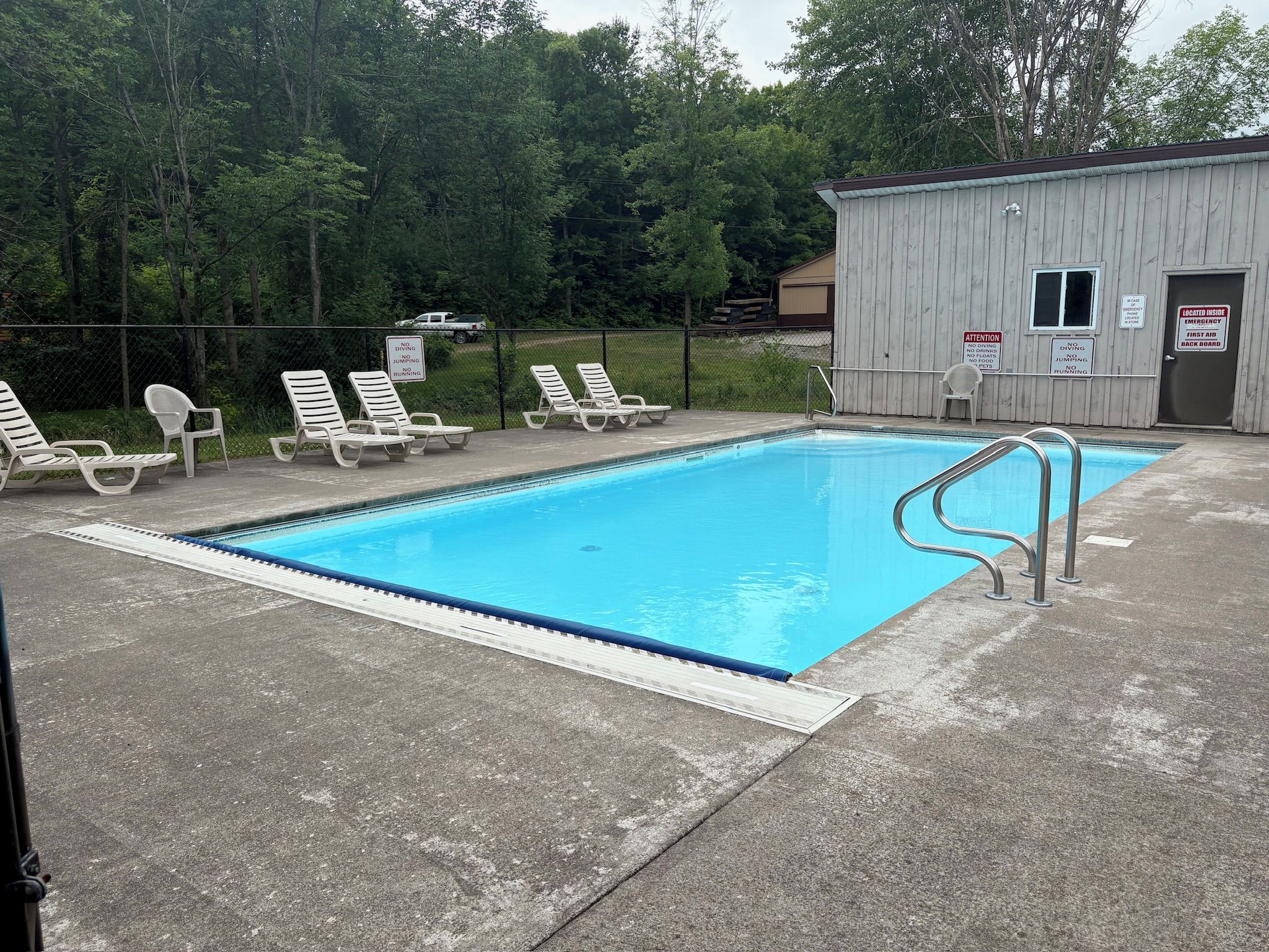 A swimming pool with lounge chairs and a small building with emergency signs.