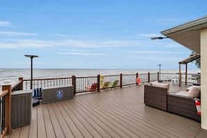 A wooden deck with outdoor furniture, a view of the sea, and a lifebuoy. - Peaceful Lake Ontario waterfront & sunsets (Lyndonville)