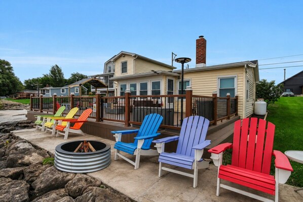 Una terraza con sillas Adirondack de colores vivos y un brasero.