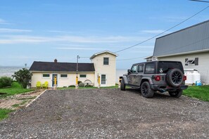 A gravel driveway leading to a house with a garage and a parked Jeep. - Peaceful Lake Ontario waterfront & sunsets (Lyndonville)