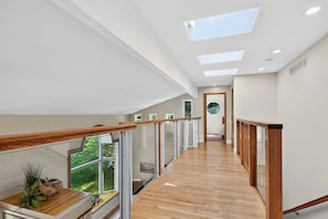 Ein modernes Interieur mit Holzboden, Glasgeländern und Oberlichtern.