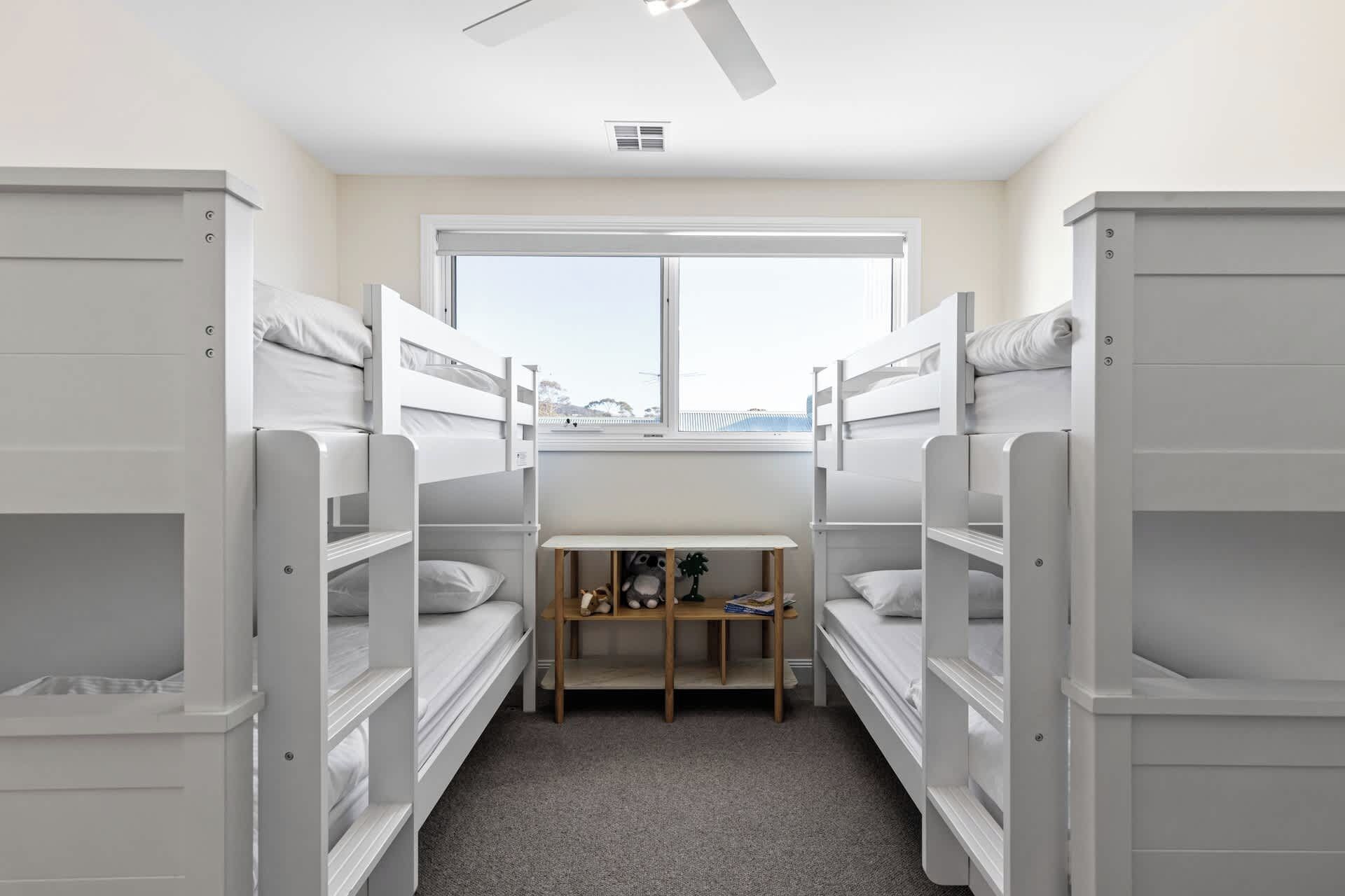 A room with bunk beds, a window, and a desk with toys.