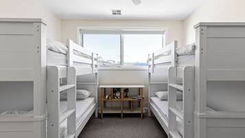 A room with bunk beds, a window, and a desk with toys.
