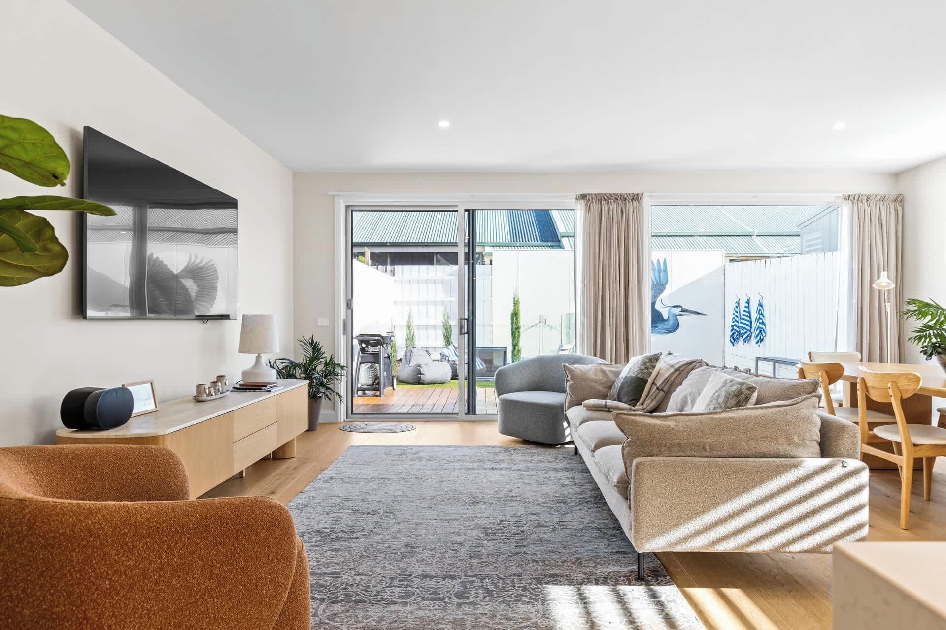 A modern living room with a sofa, a coffee table, and a dining area with chairs.