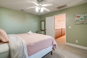 A bedroom with a bed, a ceiling fan, a door leading to a staircase, and a wall with a bird painting. - Wonderful 6-bedroom estate with pool in charming Bagdad, KY. (Bagdad)