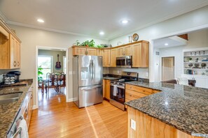 A modern kitchen with granite countertops, stainless steel appliances, wooden cabinets, and a dining area with a view. - Wonderful 6-bedroom estate with pool in charming Bagdad, KY. (Bagdad)