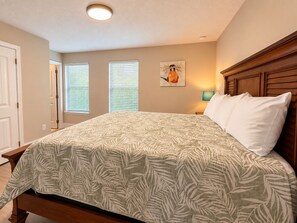 A bedroom with a bed, a nightstand, a lamp, and a painting on the wall. - Family-Friendly Luxury Villa | Sleeps 14 | Private Pool, Game Room & More! (Davenport)