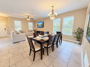 A dining area with a table set for six, a ceiling fan, and a wall-mounted TV. - Family-Friendly Luxury Villa | Sleeps 14 | Private Pool, Game Room & More! (Davenport)