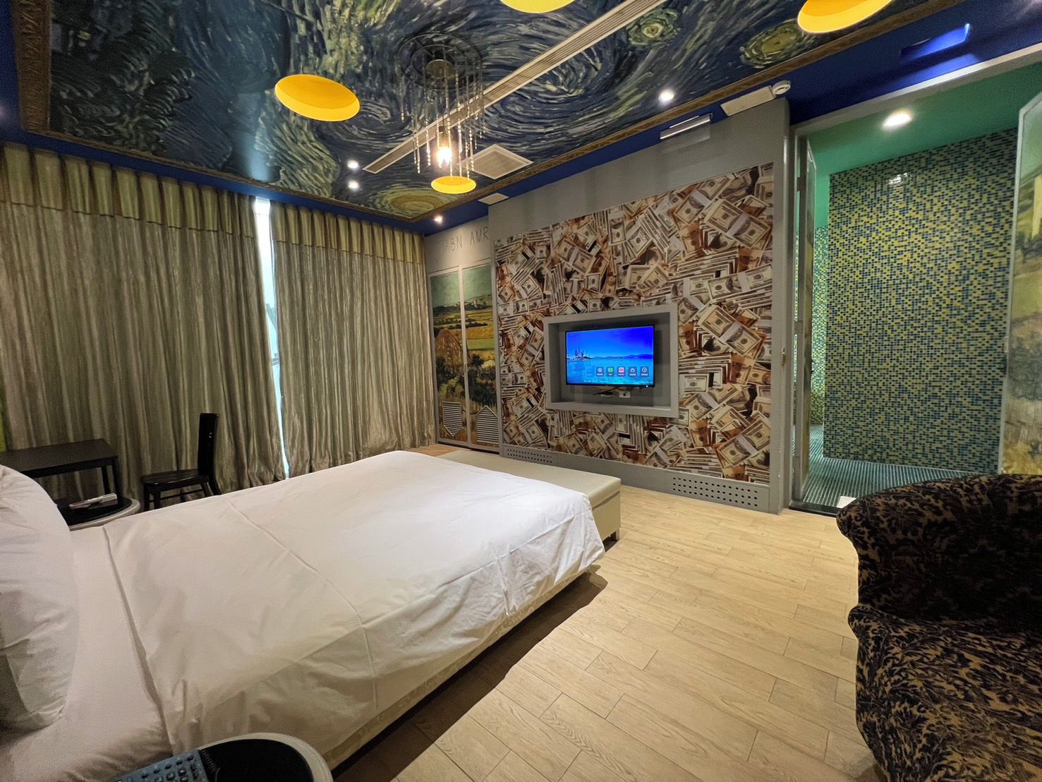 A hotel room with a bed, a television mounted on the wall, and a patterned wallpaper.