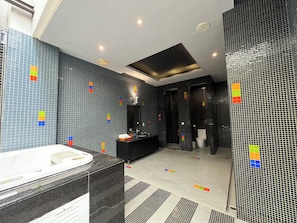 A modern bathroom with a large bathtub, a black vanity, and a shower area.