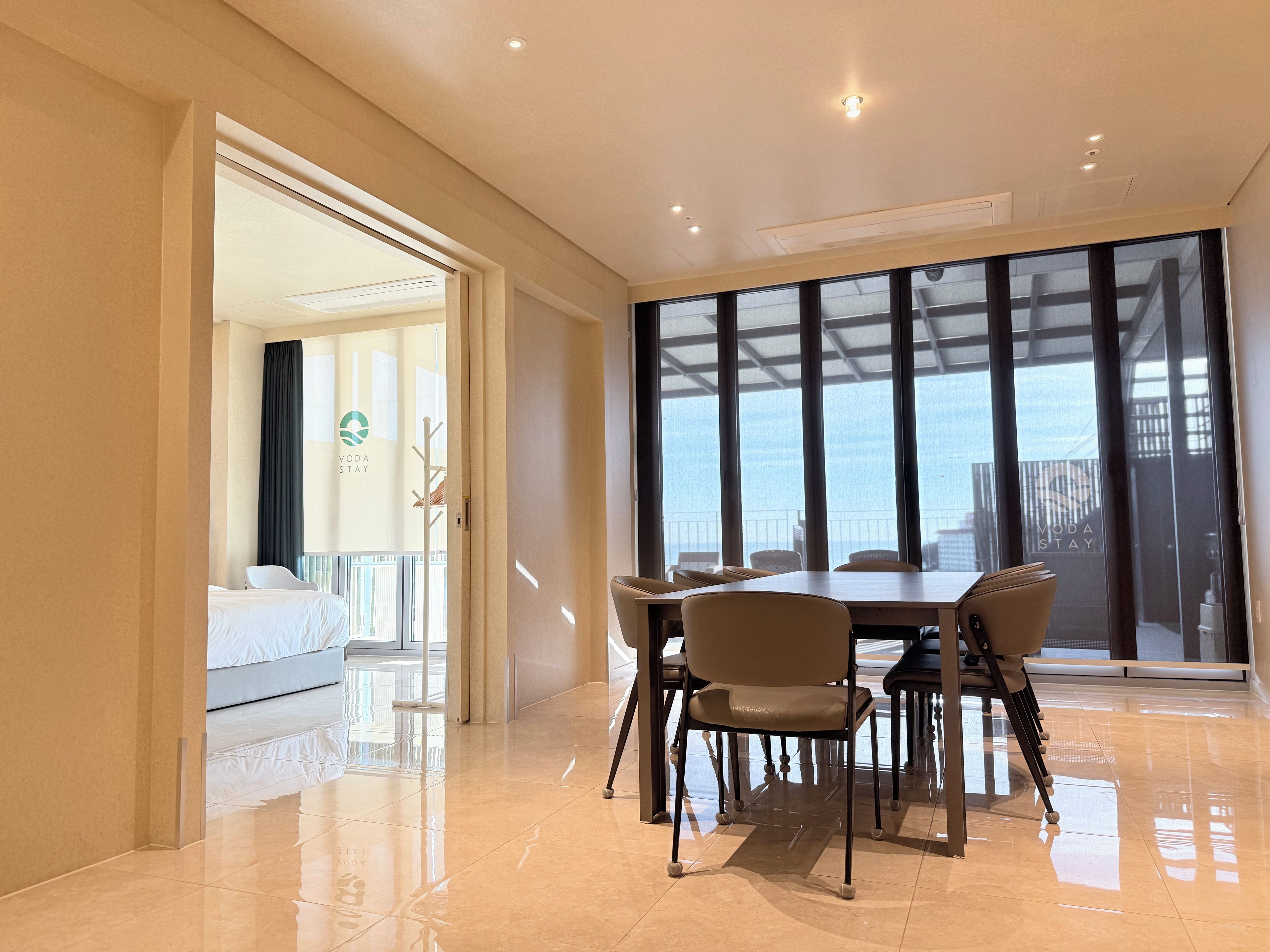 A hotel room with a bed, a dining area with a table and chairs, and a large window offering a view.
