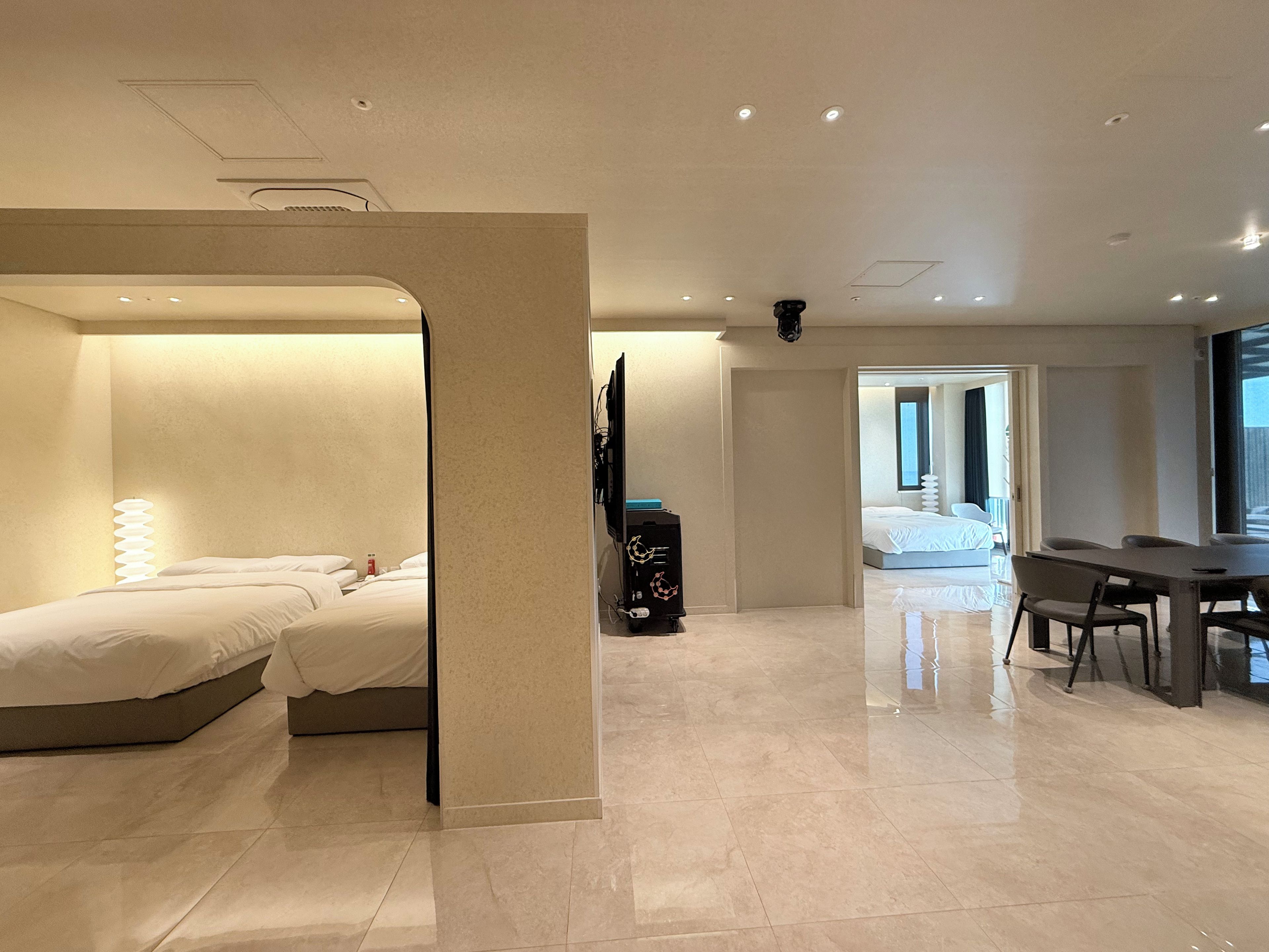 Habitación de hotel con cama, escritorio y una silla. Se observa un baño al fondo.