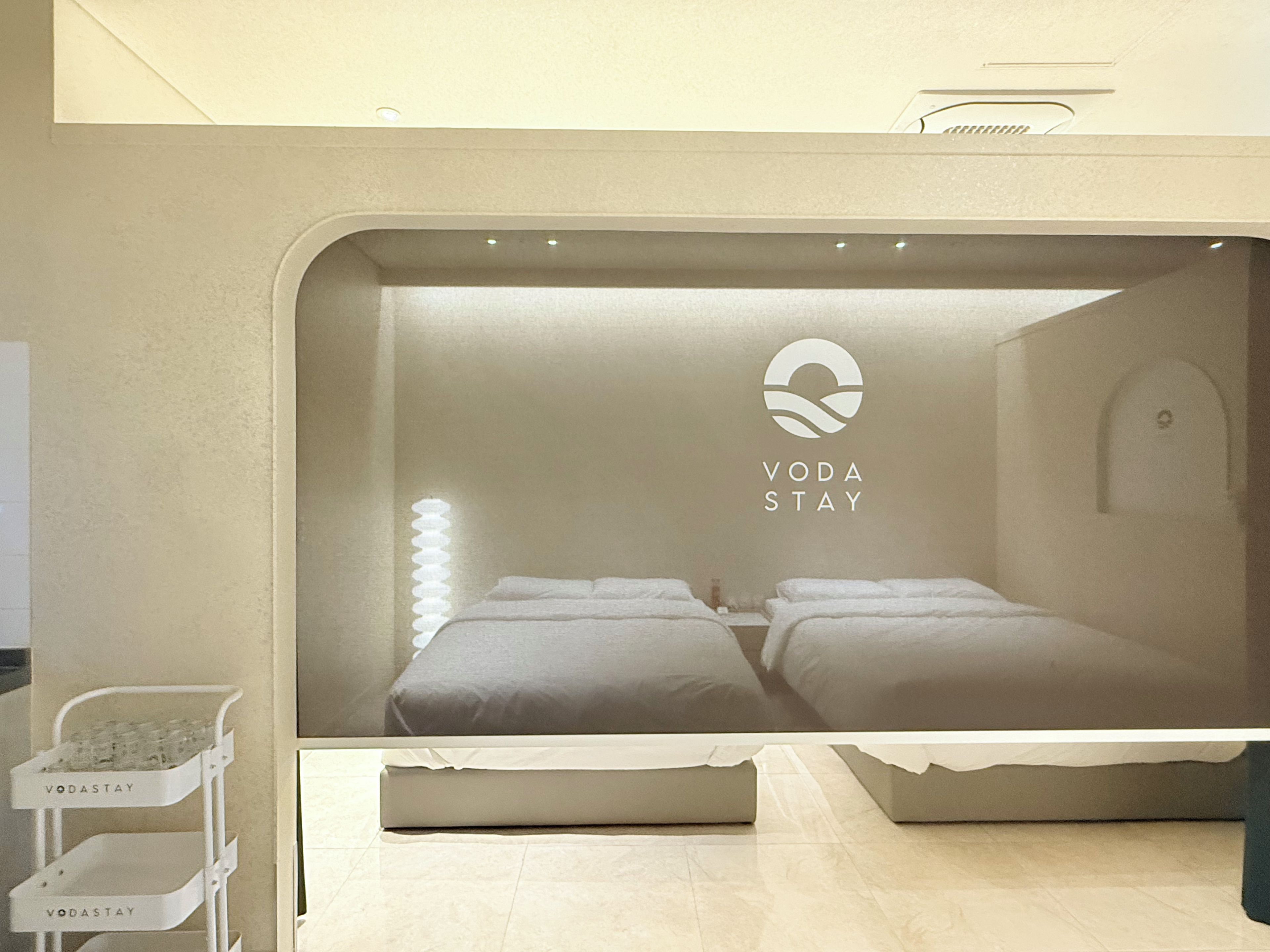 A hotel room with a bed, a bedside table, and a wall-mounted light fixture.