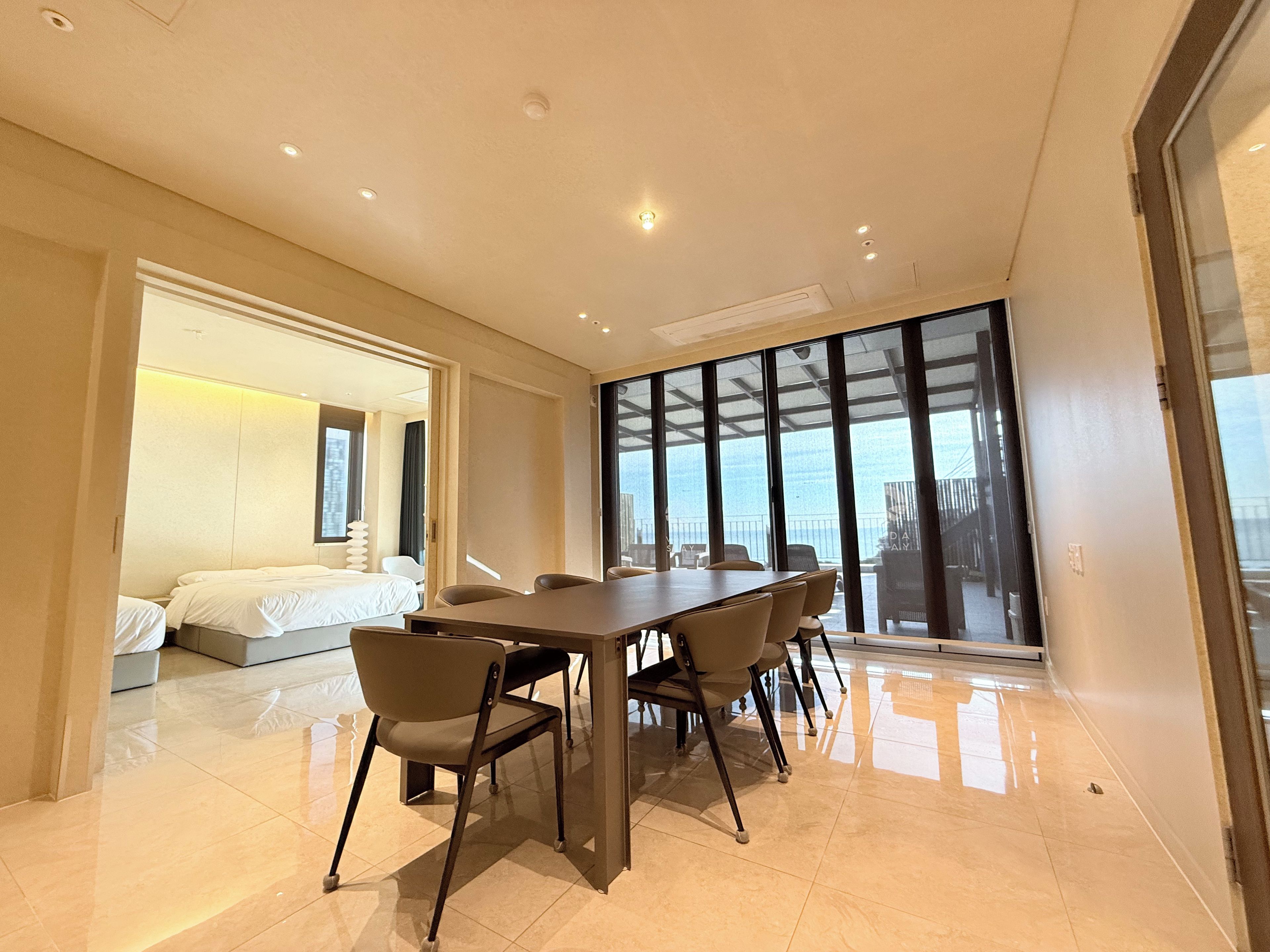 Habitación de hotel moderna con una cama grande, una mesa de comedor con sillas y un balcón con vistas.