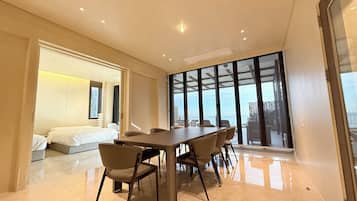 Habitación de hotel moderna con una cama grande, una mesa de comedor con sillas y un balcón con vistas.