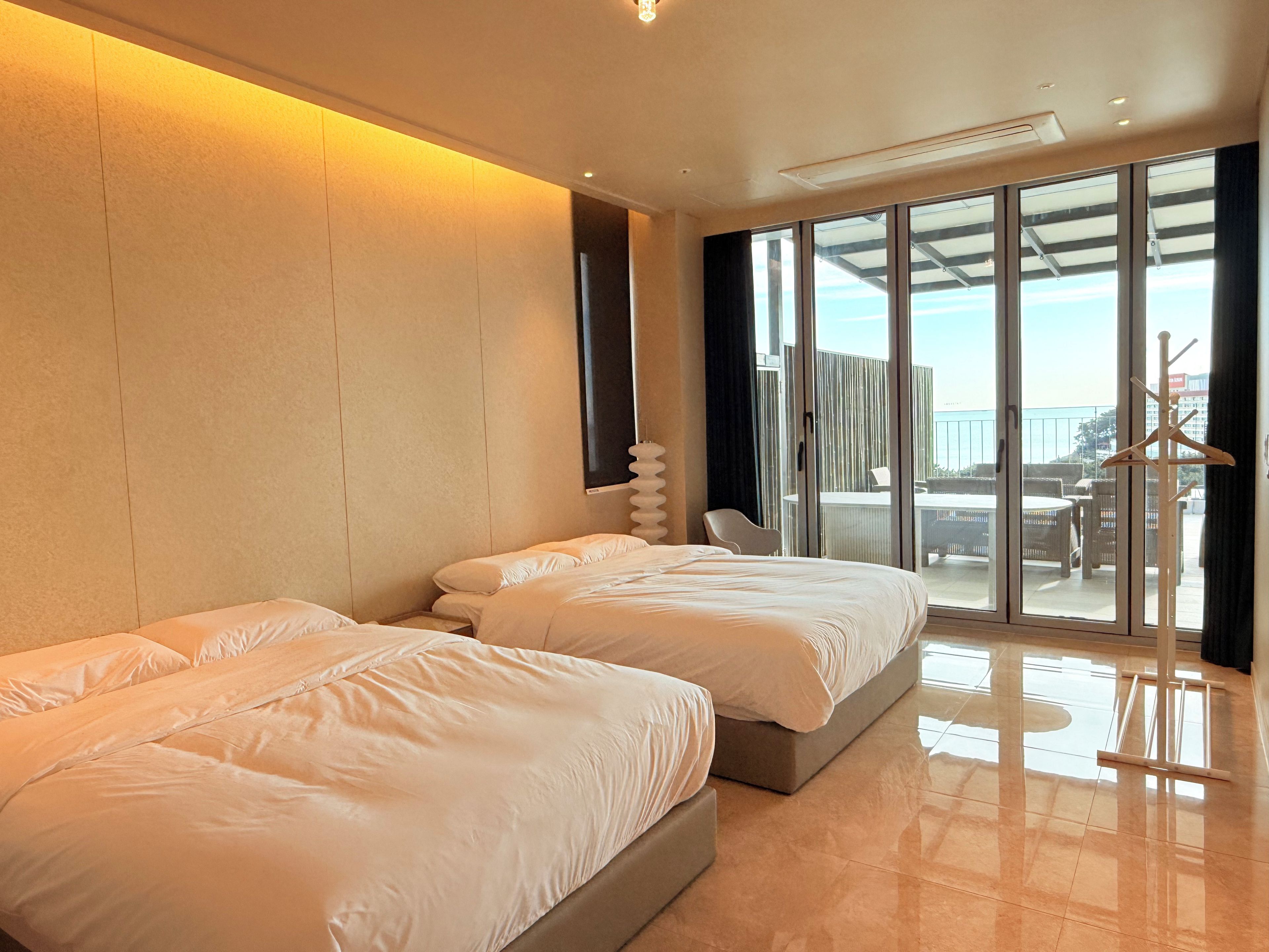 Une chambre d’hôtel avec deux lits, une grande fenêtre et une vue sur l’extérieur.