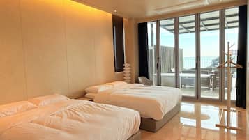 Habitación de hotel con dos camas, un ventanal grande y vistas al exterior.
